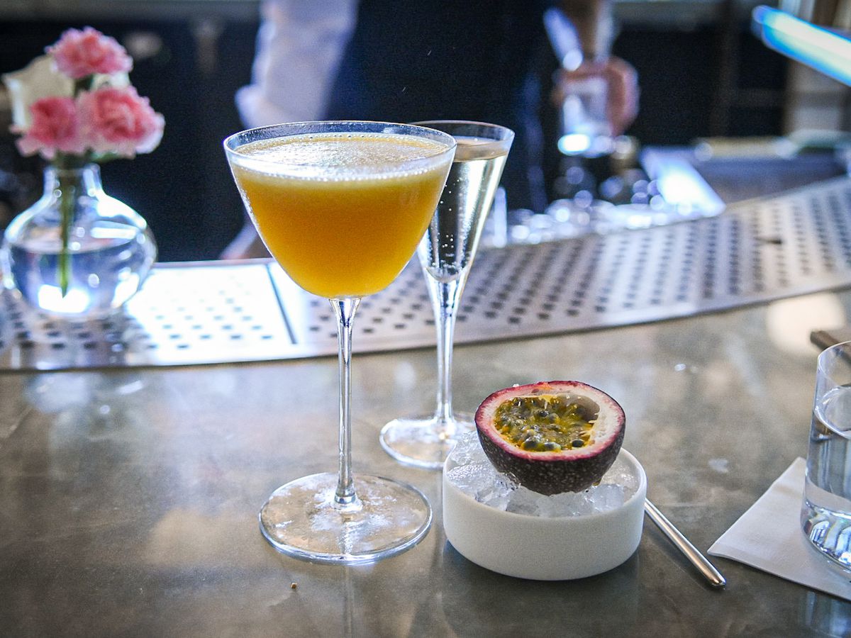 Một ly martini trái cây với rượu sâm panh và nửa quả chanh dây trong một bát nhỏ đá bào.