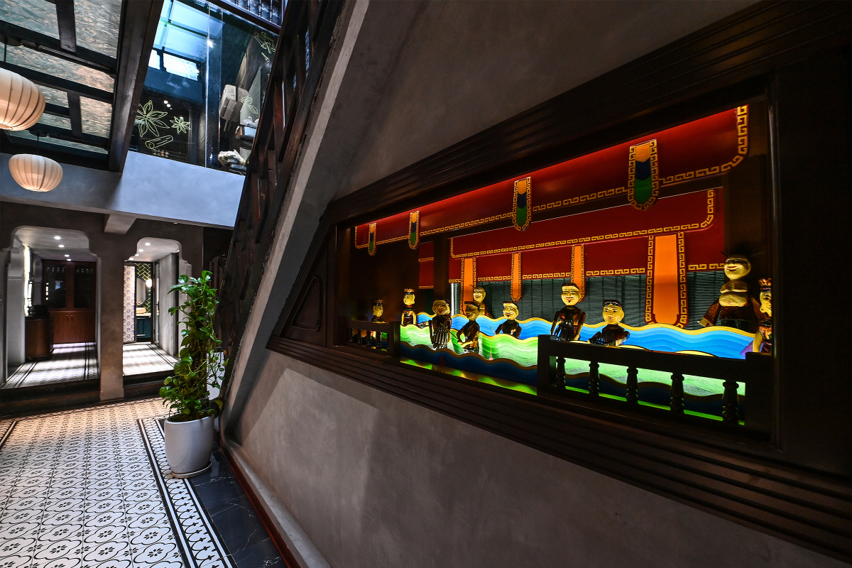 Hình ảnh về văn hóa múa rối nước được lồng ghép ở khu vực cầu thang dẫn lên tầng hai của nhà hàng.